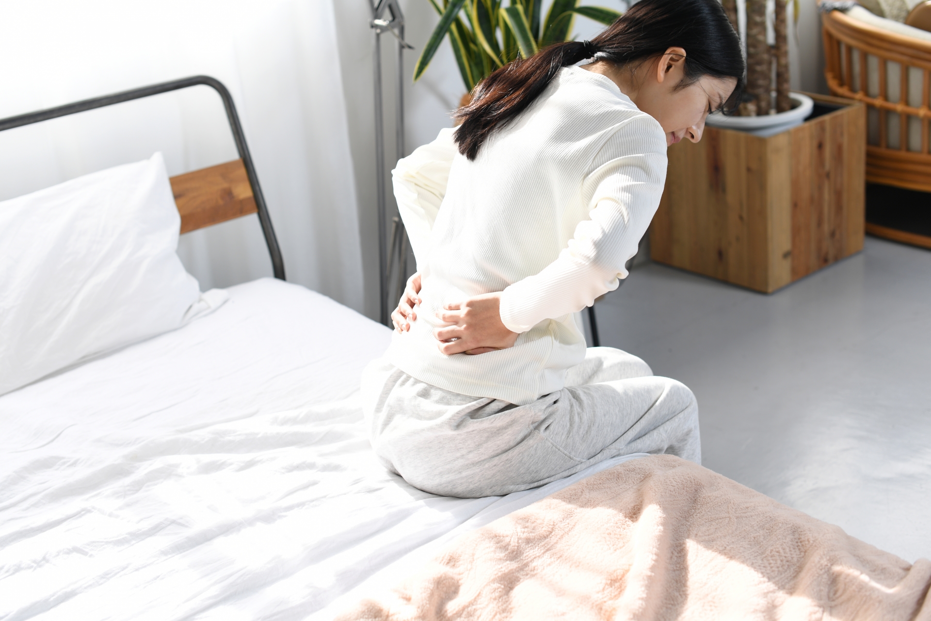 朝起き上がる時に腰痛で悩む女性|長浜市